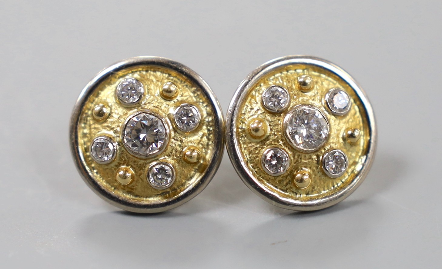 A modern pair of textured yellow metal and diamond cluster set disc earrings, with white metal border, diameter 16mm, gross weight 11.2 grams.